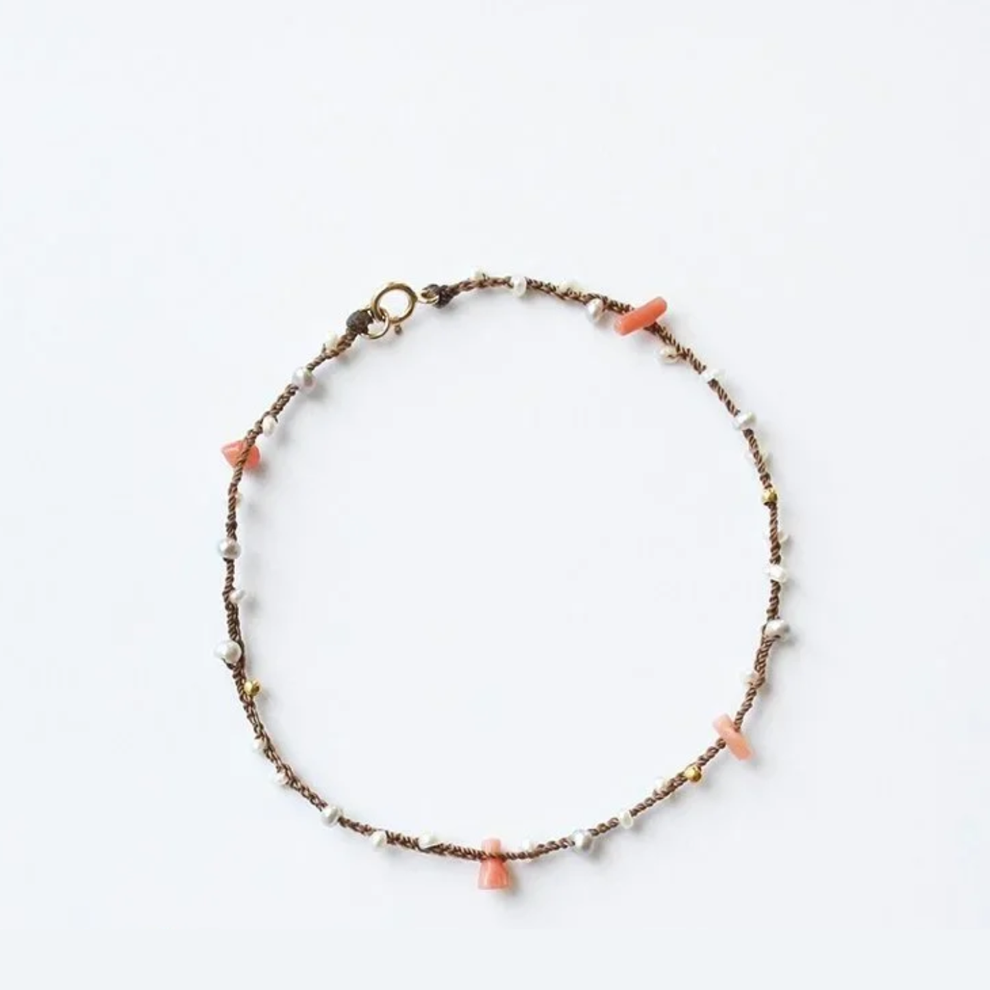 Braided pearl and coral bracelet with gold clasp and orange charm tips