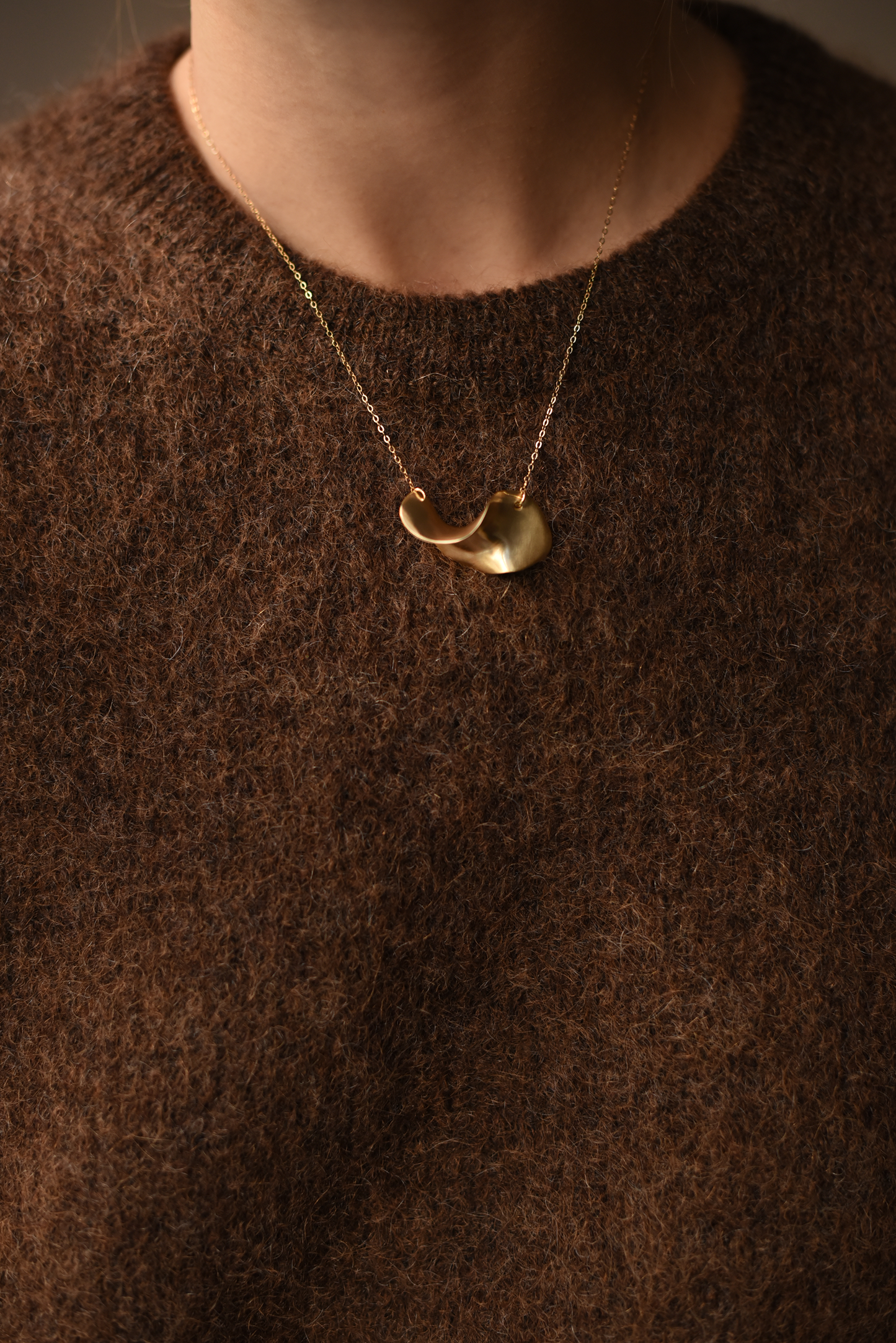 Gold open-circle pendant necklace on thin chain, worn at neckline