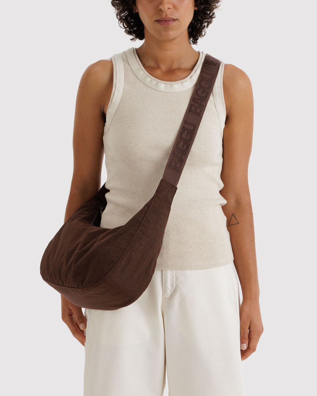 Brown nylon crescent bag worn crossbody with strap across shoulder