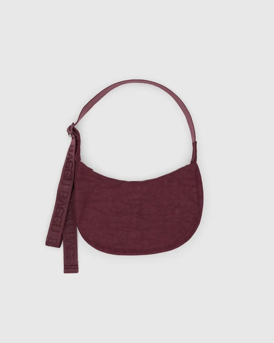 Small crescent nylon crossbody bag in deep burgundy with curved shoulder strap and tag