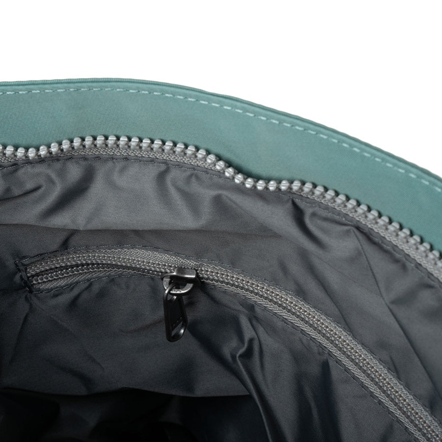 Interior view of teal nylon crossbody bag with zip pocket and gray zipper hardware