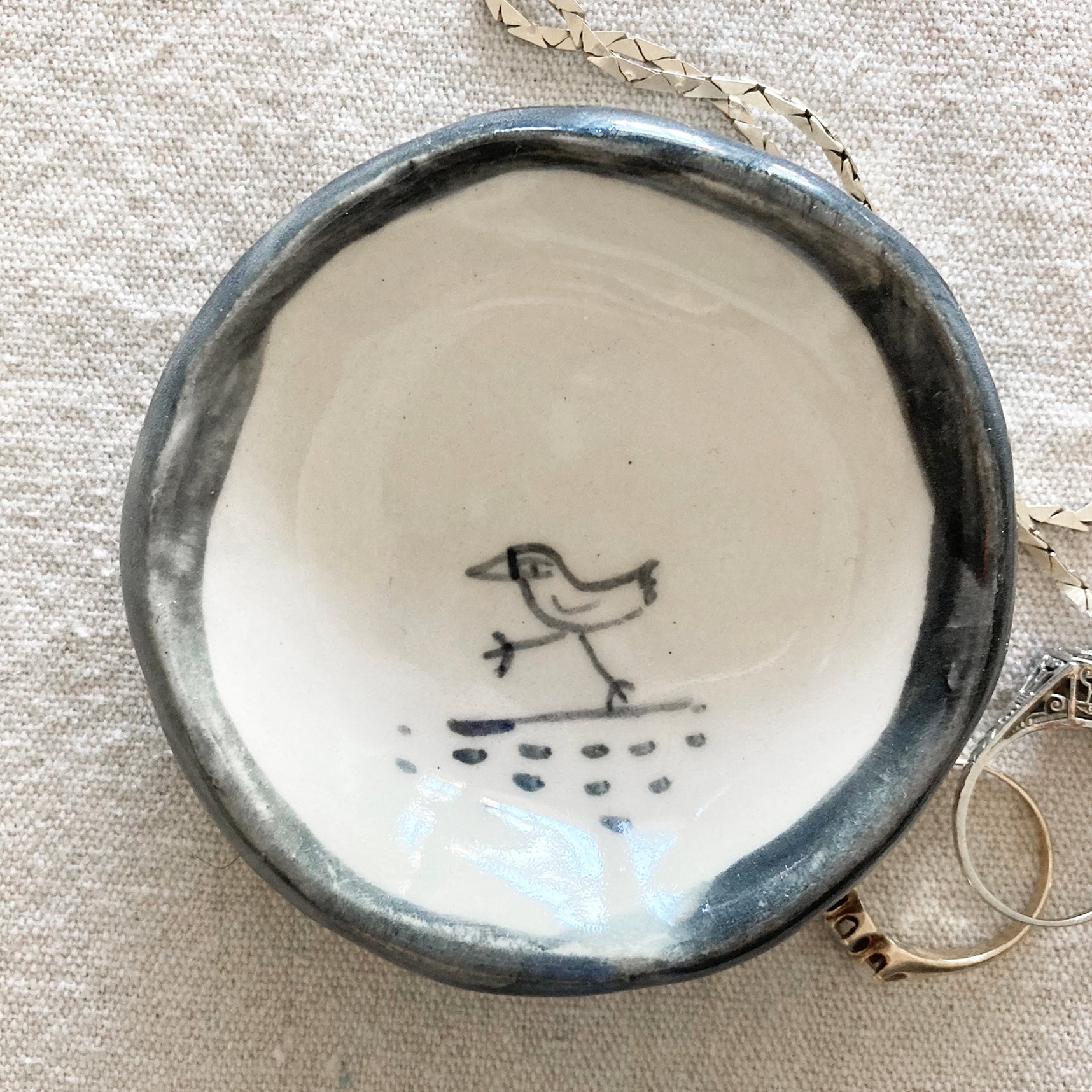 Handmade ceramic bird trinket dish, top view of blue rim and raindrop pattern