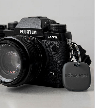 Key finder tag clipped to a camera strap, dark gray plastic