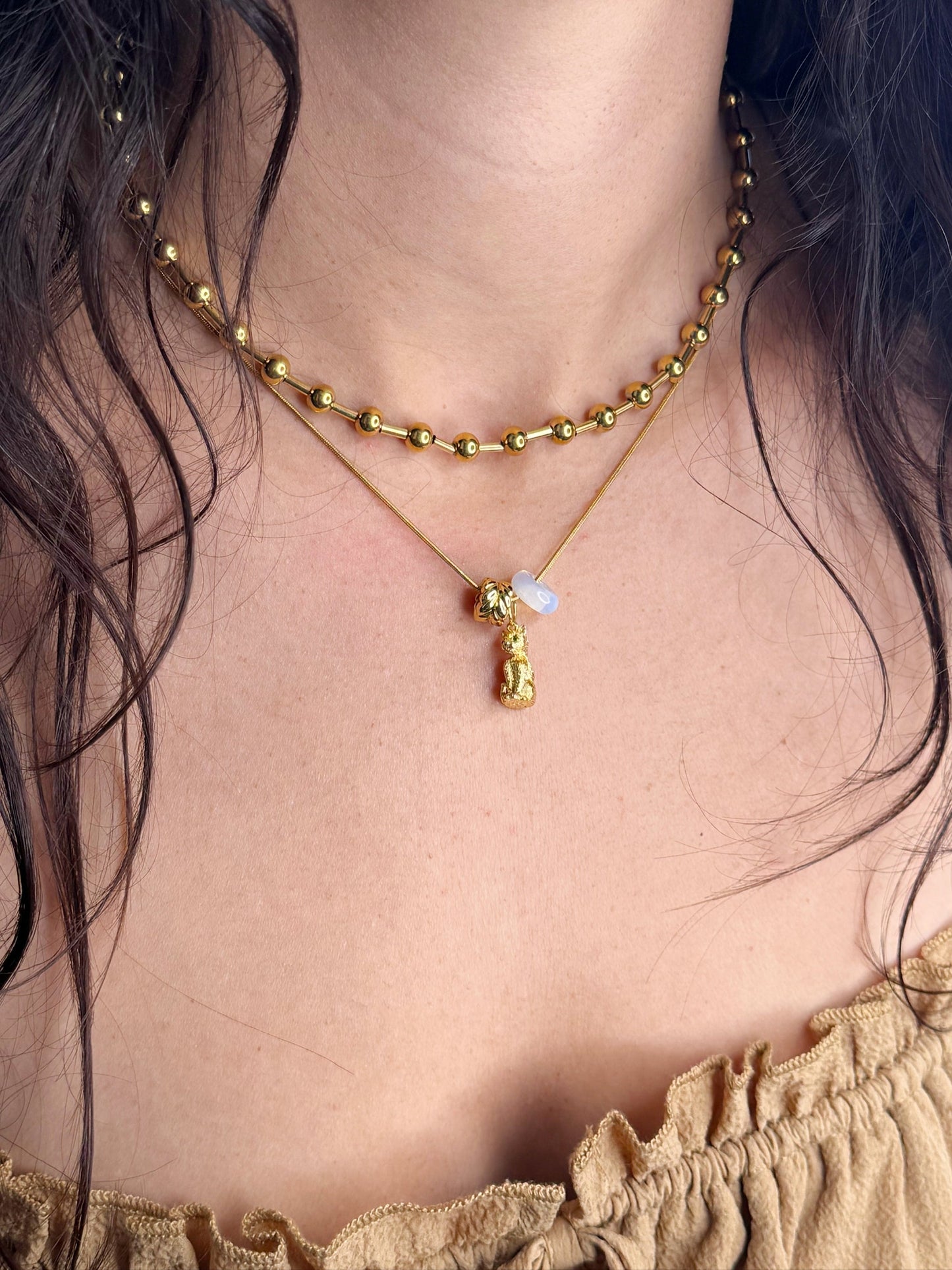 Gold-tone charm spacer bead on a beaded necklace with small dangling charm