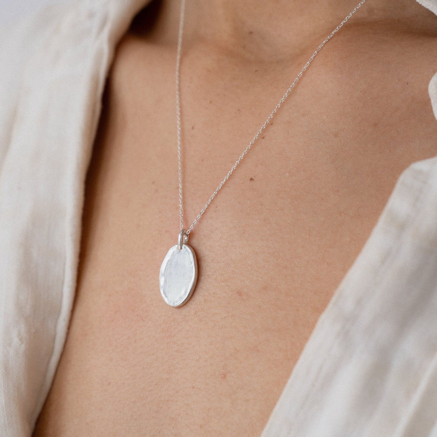 Silver oval pendant necklace with small bail on delicate chain close-up
