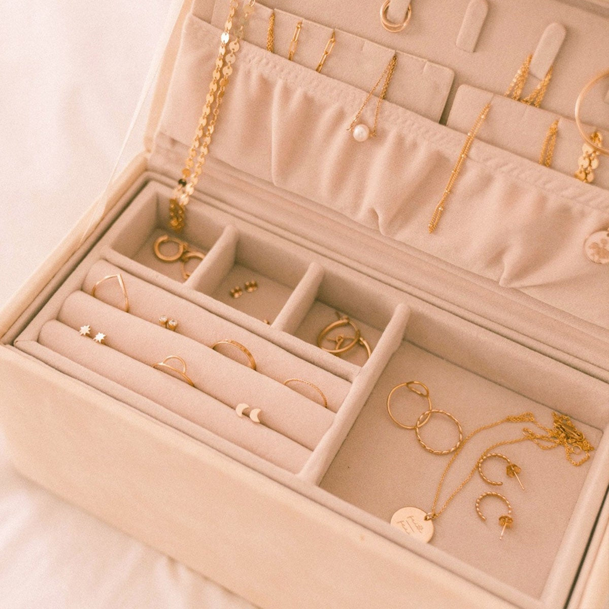 Open cream vegan leather jewelry box with ring slots and earring hooks.