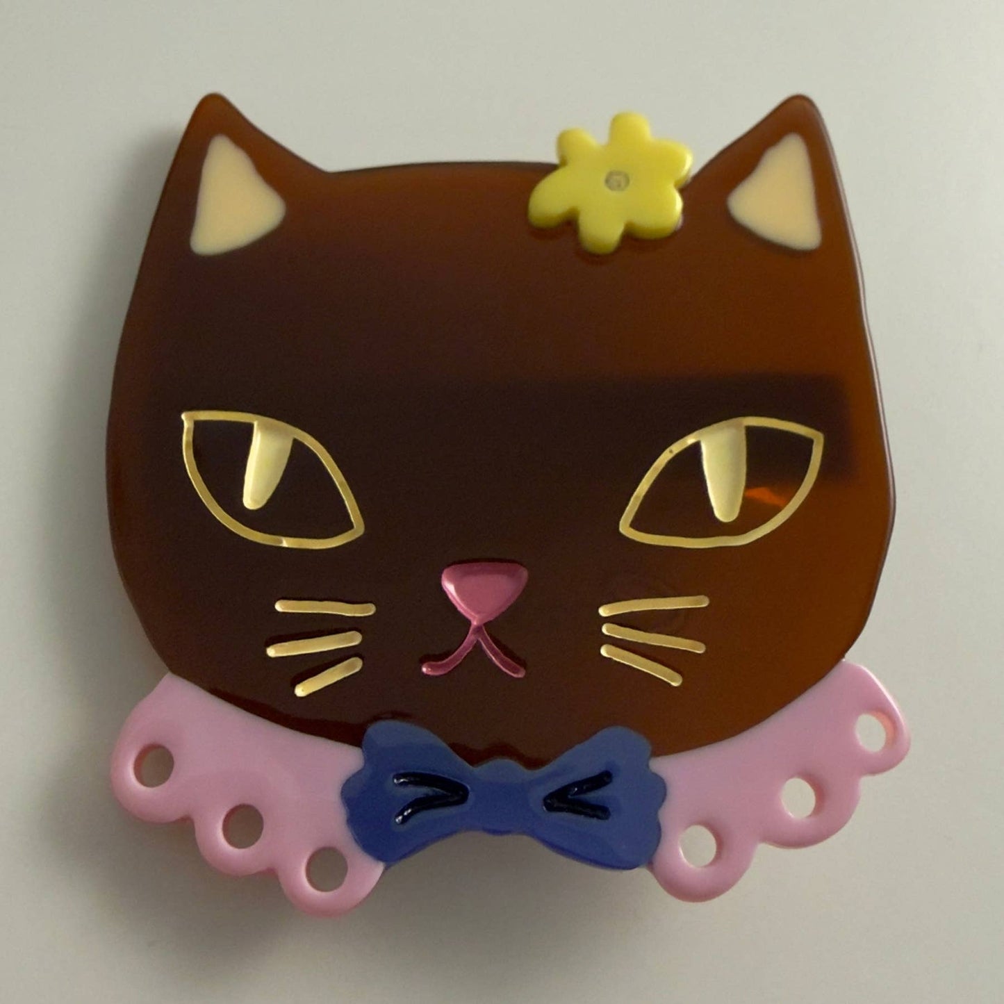 Brown cat-shaped alligator clip with yellow flower, pink nose, blue bow detail