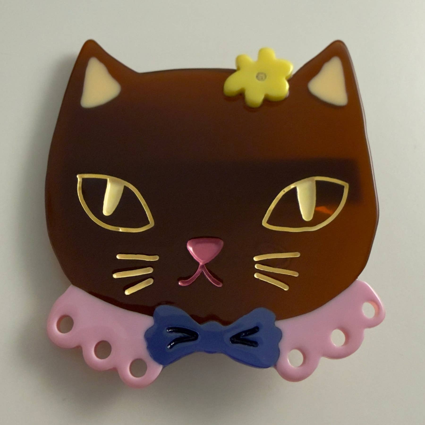Brown cat-shaped alligator clip with yellow flower, pink nose, blue bow detail
