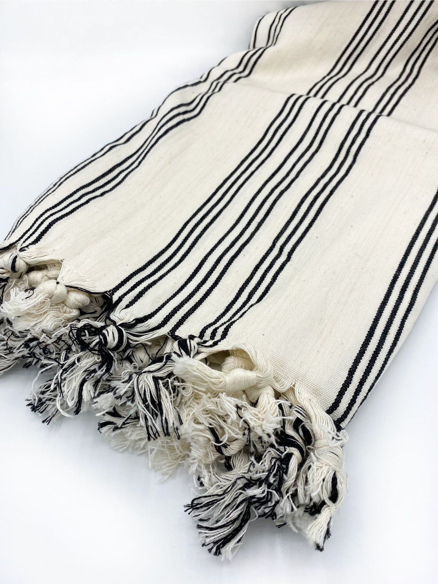 Cream fabric throw with black stripe bands and decorative fringed tassels