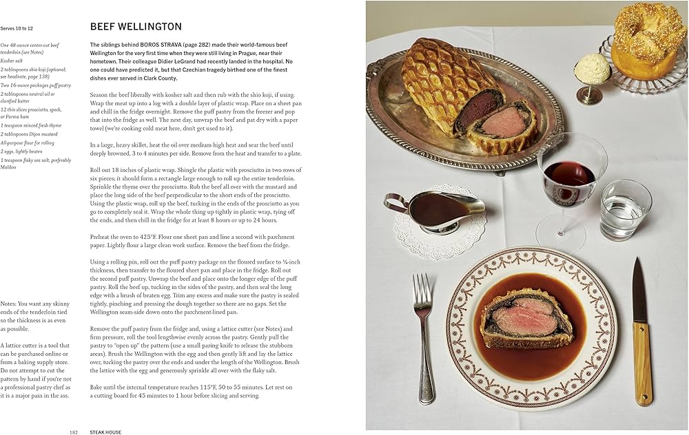 Open cookbook spread with Beef Wellington on a platter and cups and cutlery