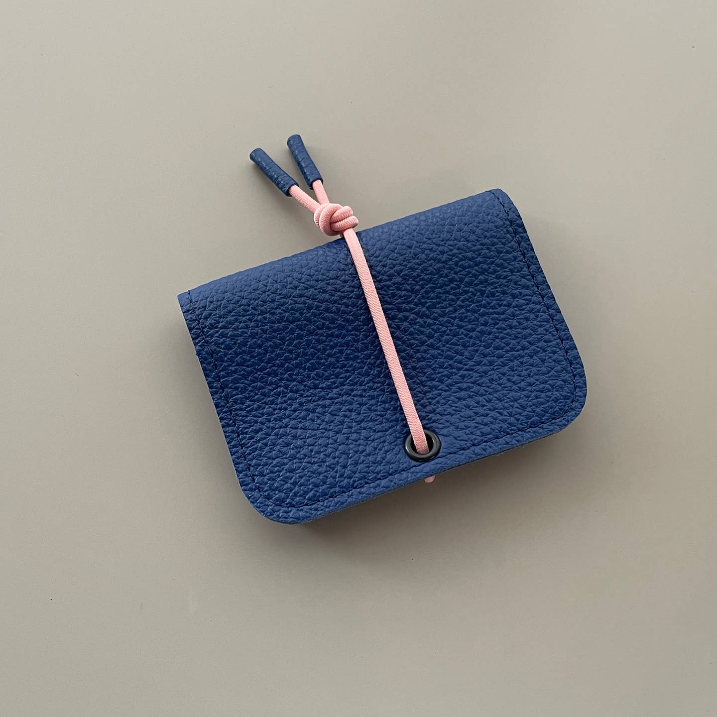 Navy leather mini wallet with knot closure and metal snap detail