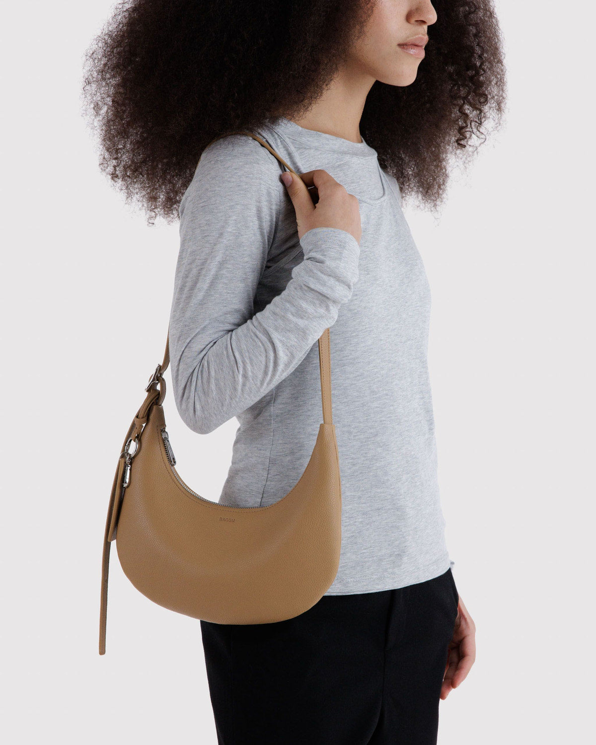 Recycled leather crescent hobo bag worn over the shoulder with long slim strap
