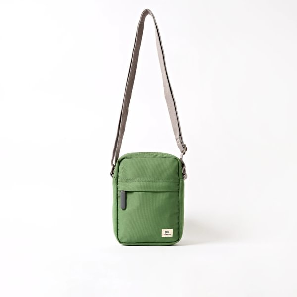 Green canvas crossbody bag with zip top, front pocket, and adjustable shoulder strap