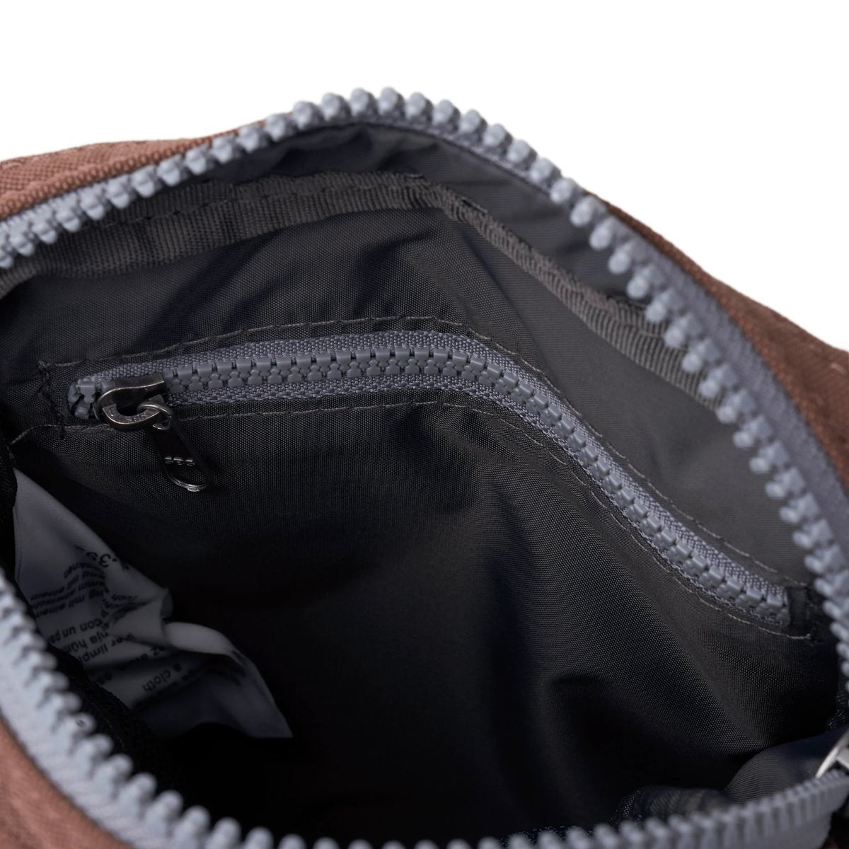 Brown crossbody bag interior with black fabric lining and zippered opening