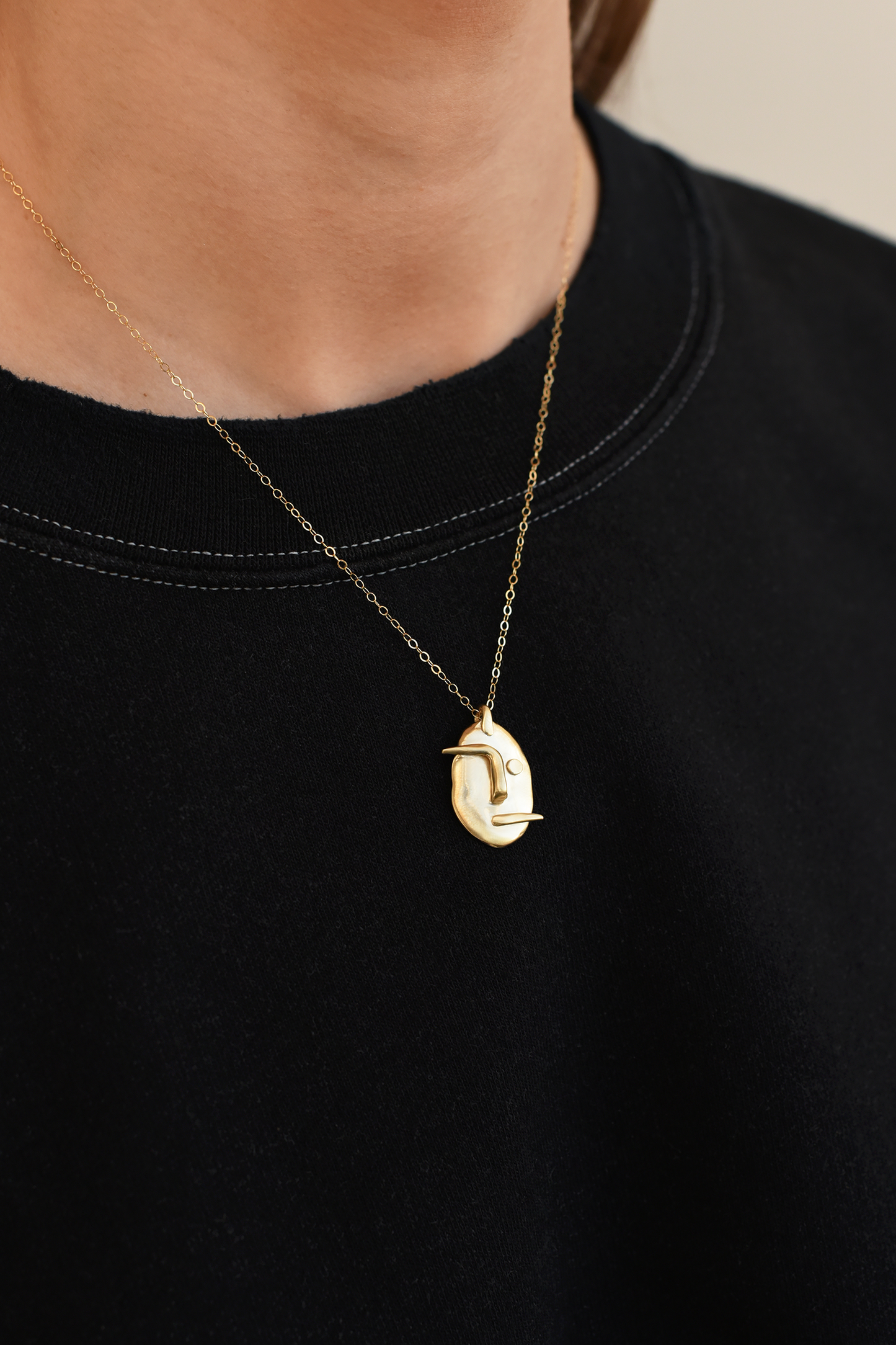 Brass face pendant necklace with gold-tone chain and small face charm