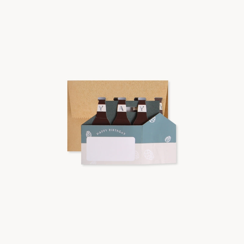 Pop-up birthday card with kraft envelope behind, showing beer-bottle pop-ups and blank insert
