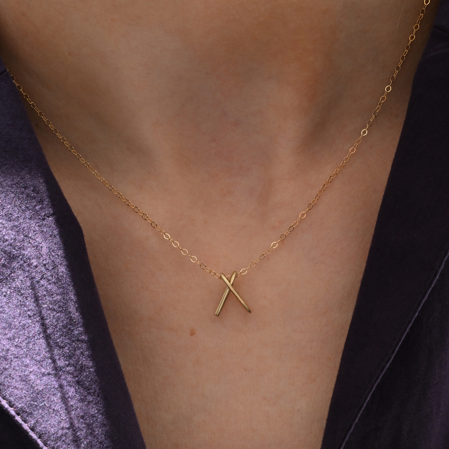 Brass chain necklace with X-shaped pendant, centered on neckline