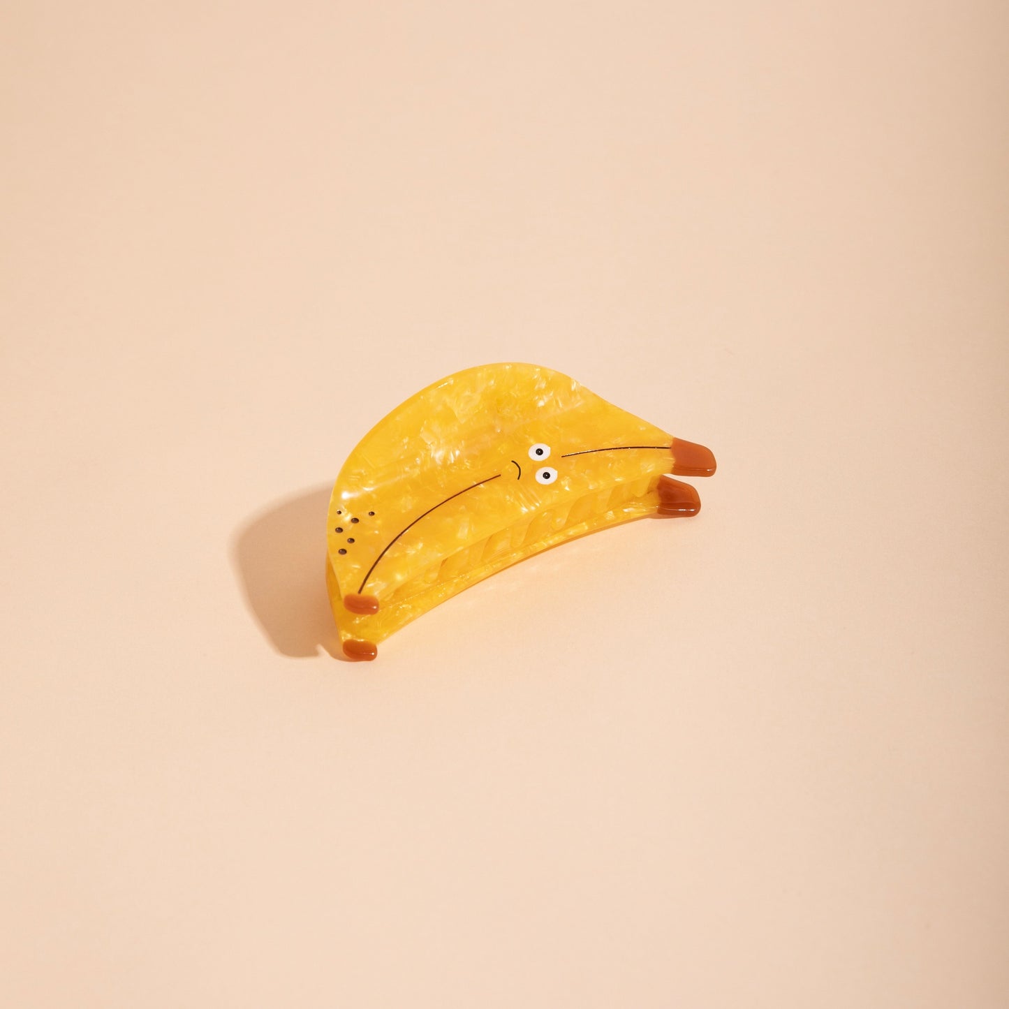 Yellow banana-shaped hair claw with speckled design and small eye details