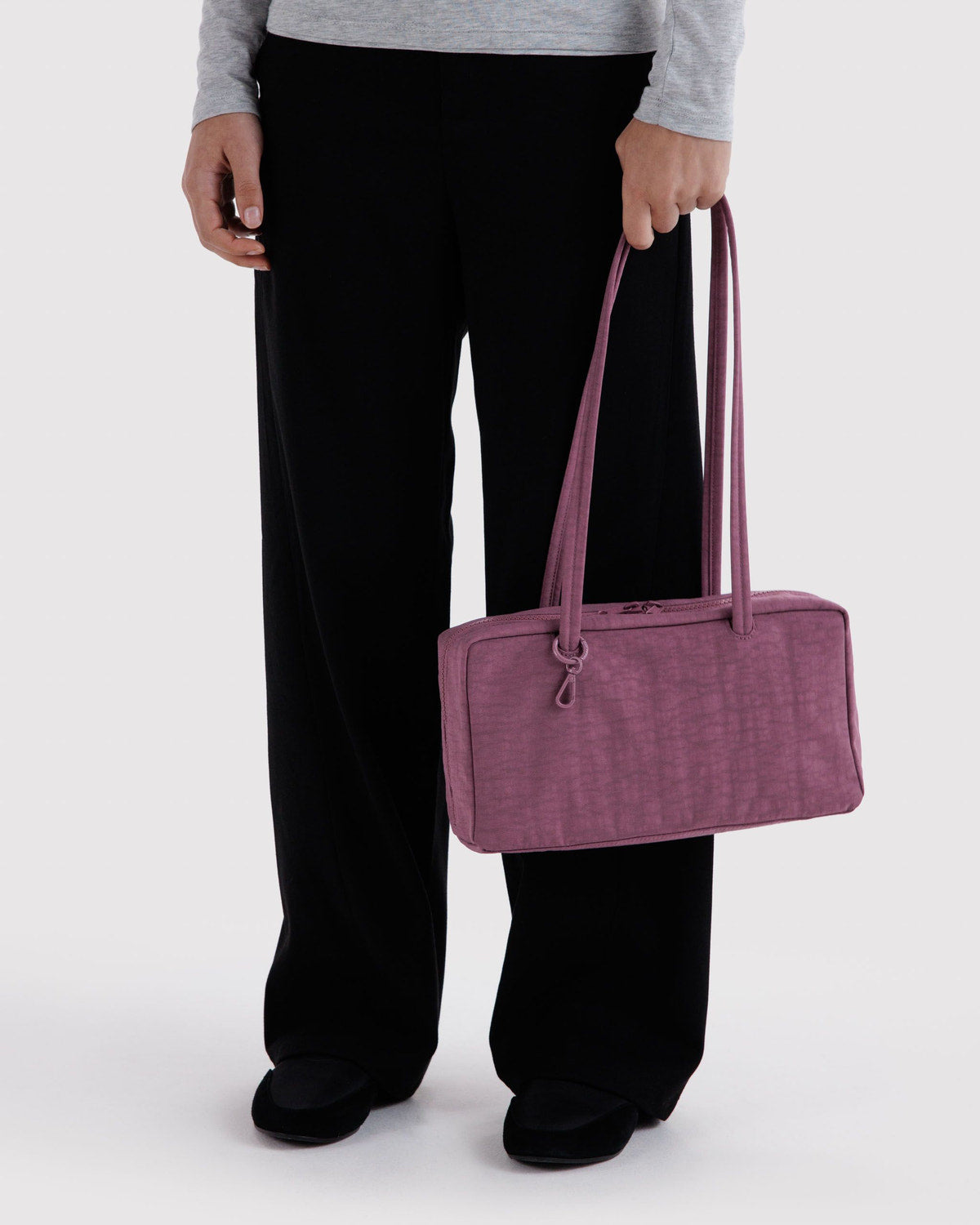 Plum purple nylon bowler bag held by long handles, front zip pocket area