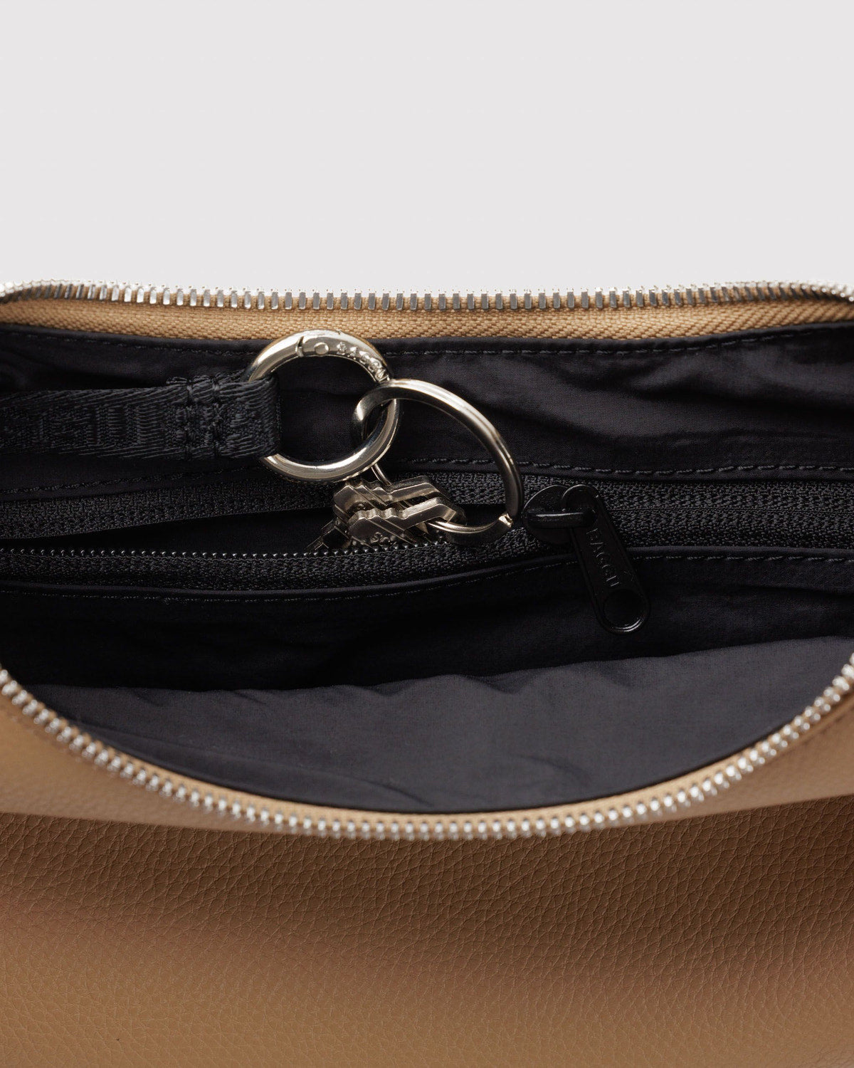 Zip-top lining detail with metal ring and chunky zipper on recycled leather crescent bag