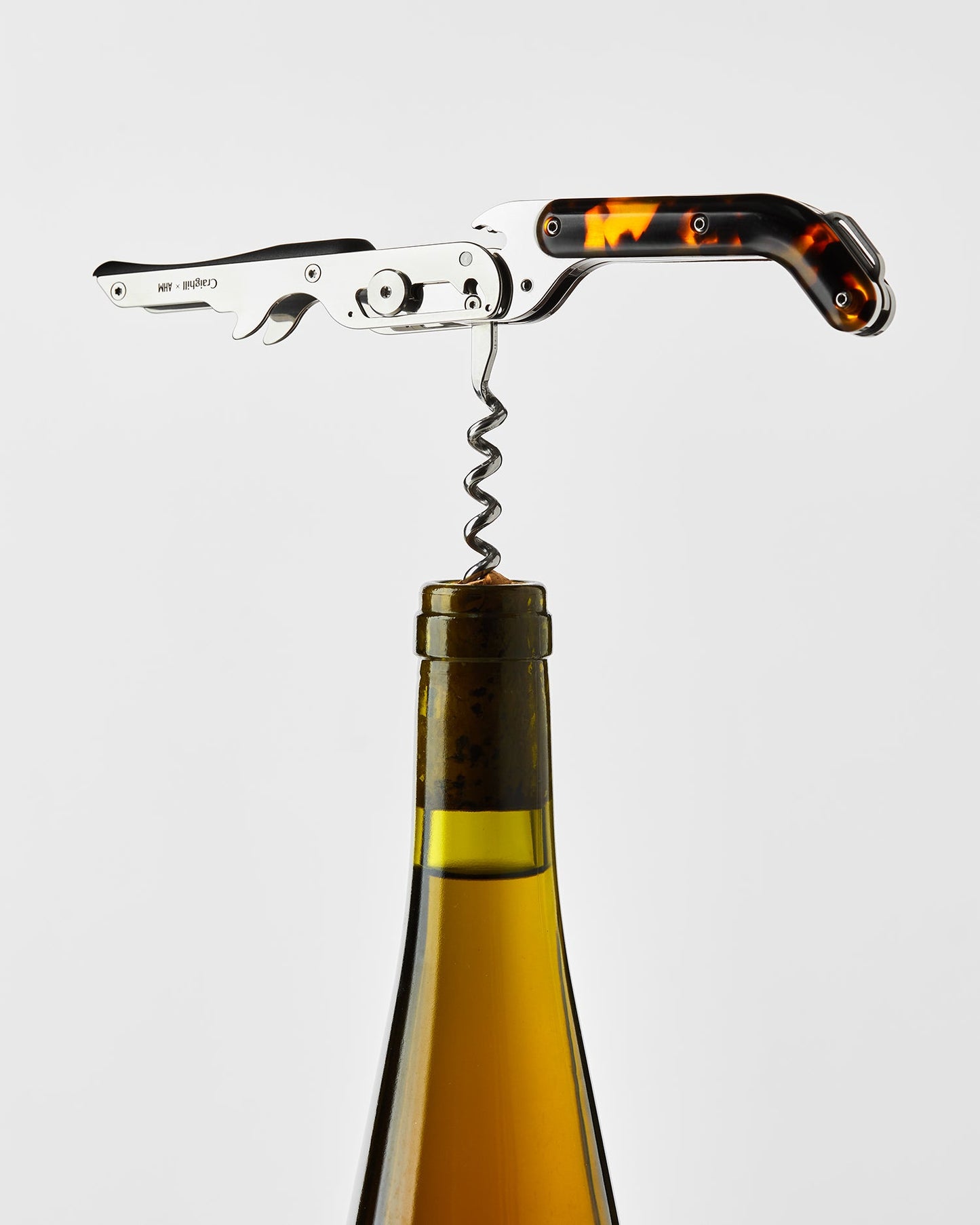 Wine corkscrew inserting into a bottle cork with amber tortoise handle