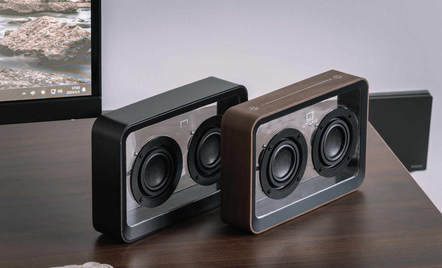 Pair of walnut see-through speakers with two black drivers each on desk