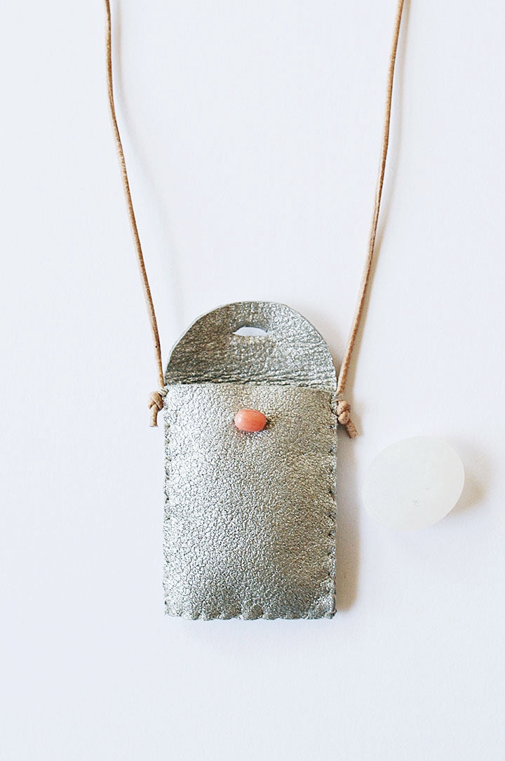 Textured silver-toned amulet pouch necklace with red bead front and cord ties