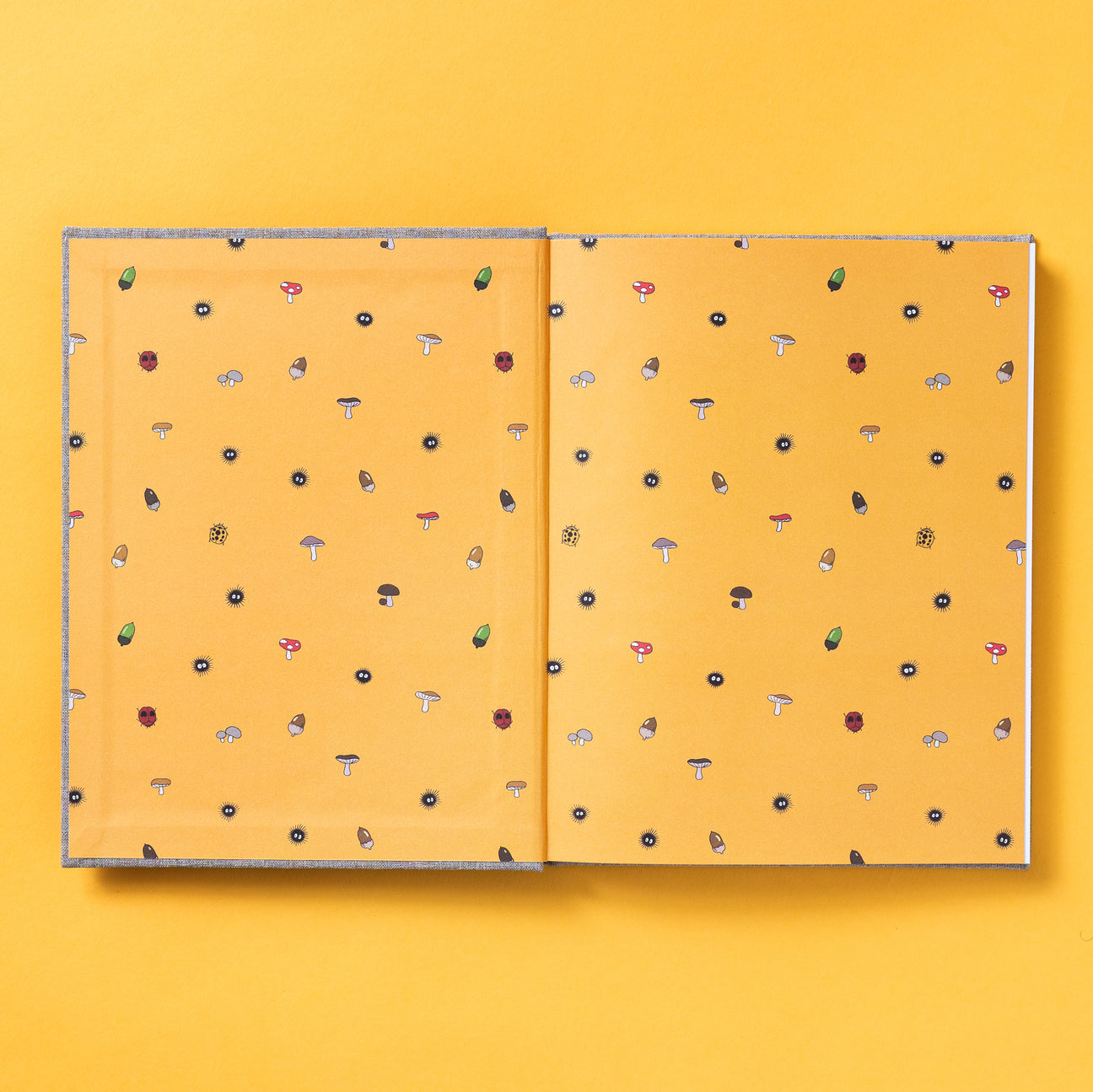 Sketchbook open with orange mushroom-pattern cover and two stitched pages, top view.
