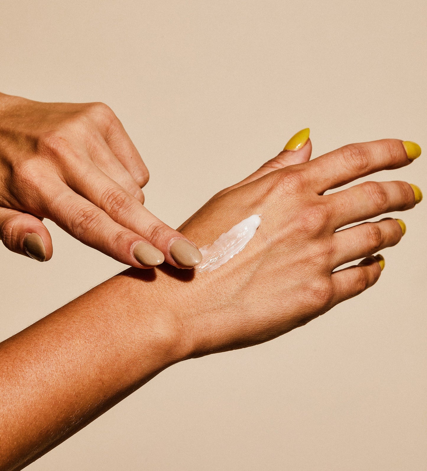 Hand applying hand cream, with white cream on fingertips