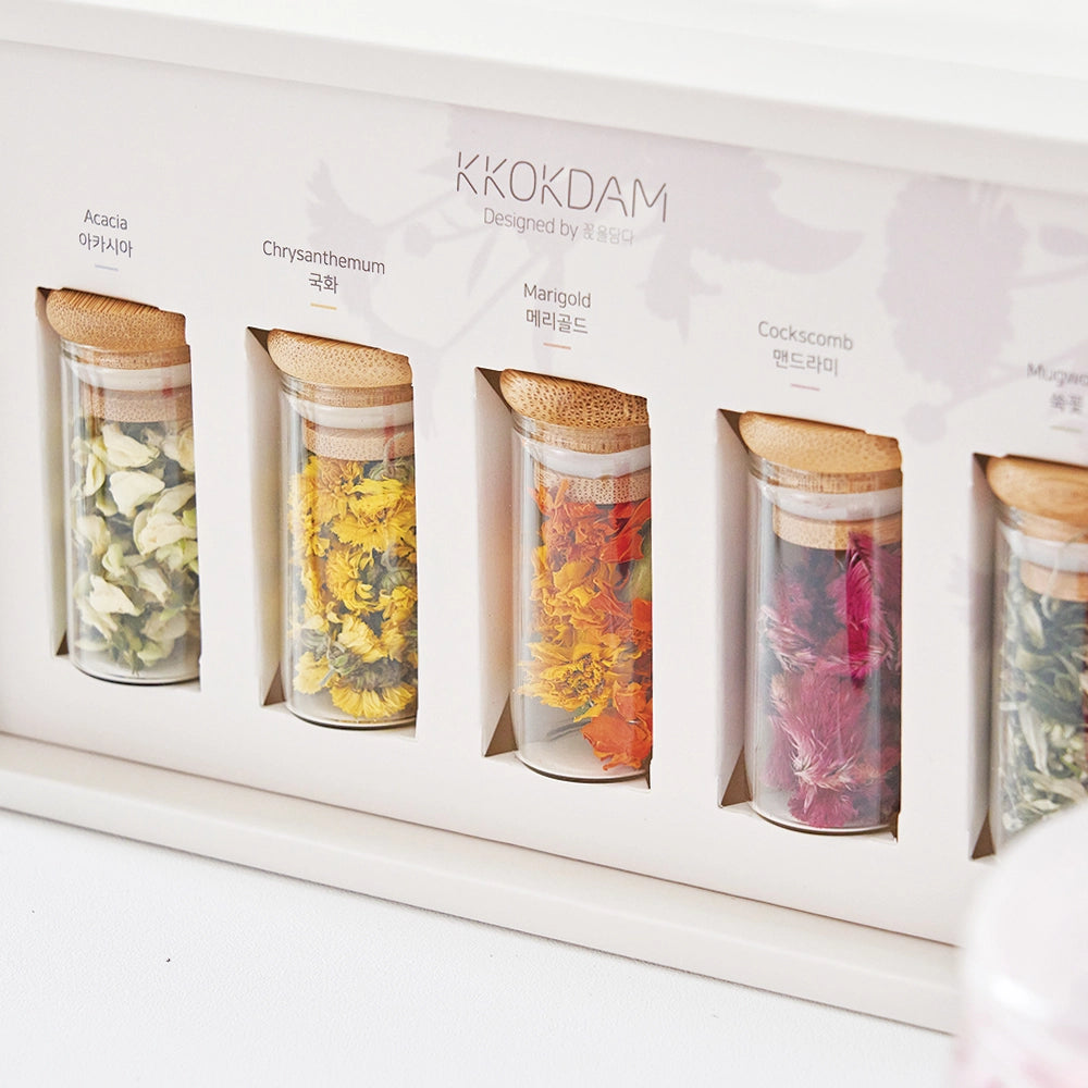Boxed flower tea sampler with multiple glass jars holding dried blossoms, close-up