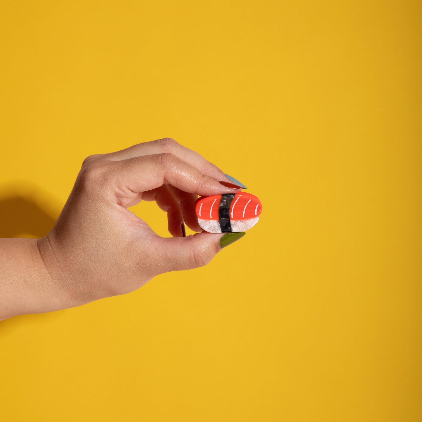 Mini red and white striped hair claw clip held in hand