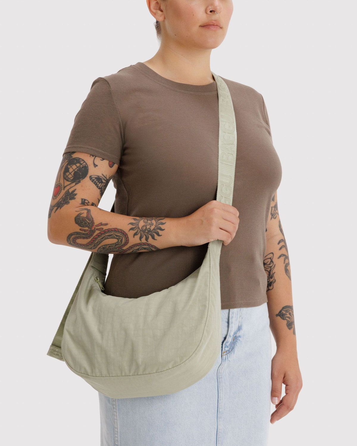 Light olive nylon crescent bag worn crossbody on model
