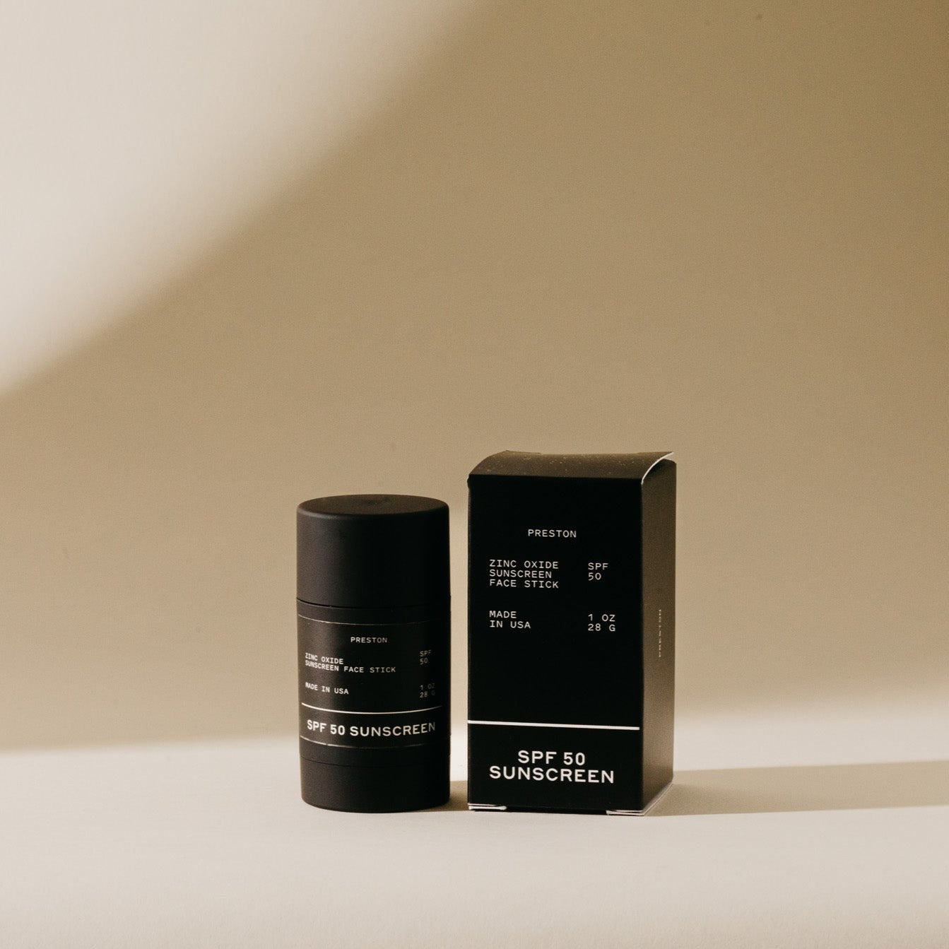 Black sunscreen stick with cardboard box labeled SPF 50 sunscreen