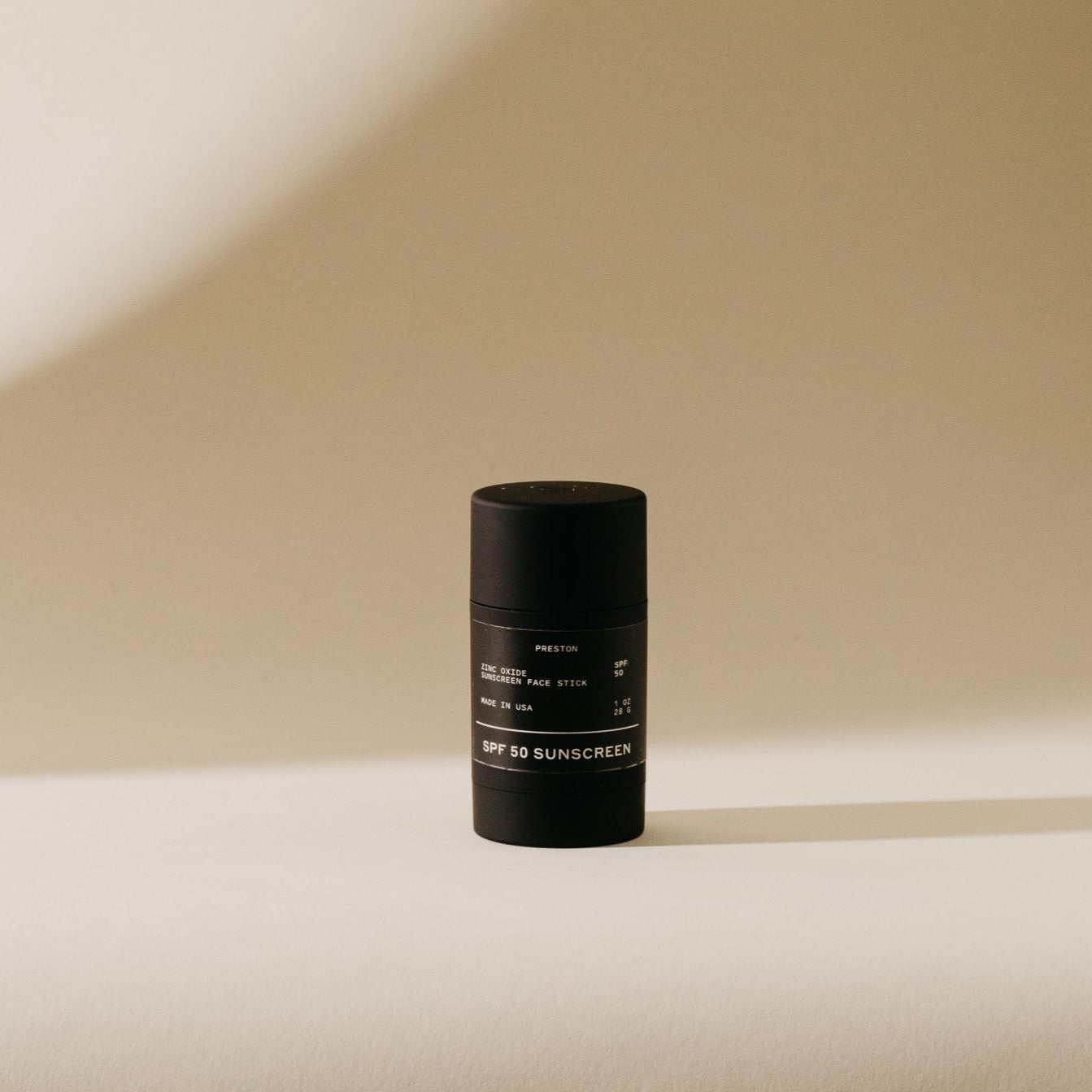 Black sunscreen stick, cylindrical with printed label
