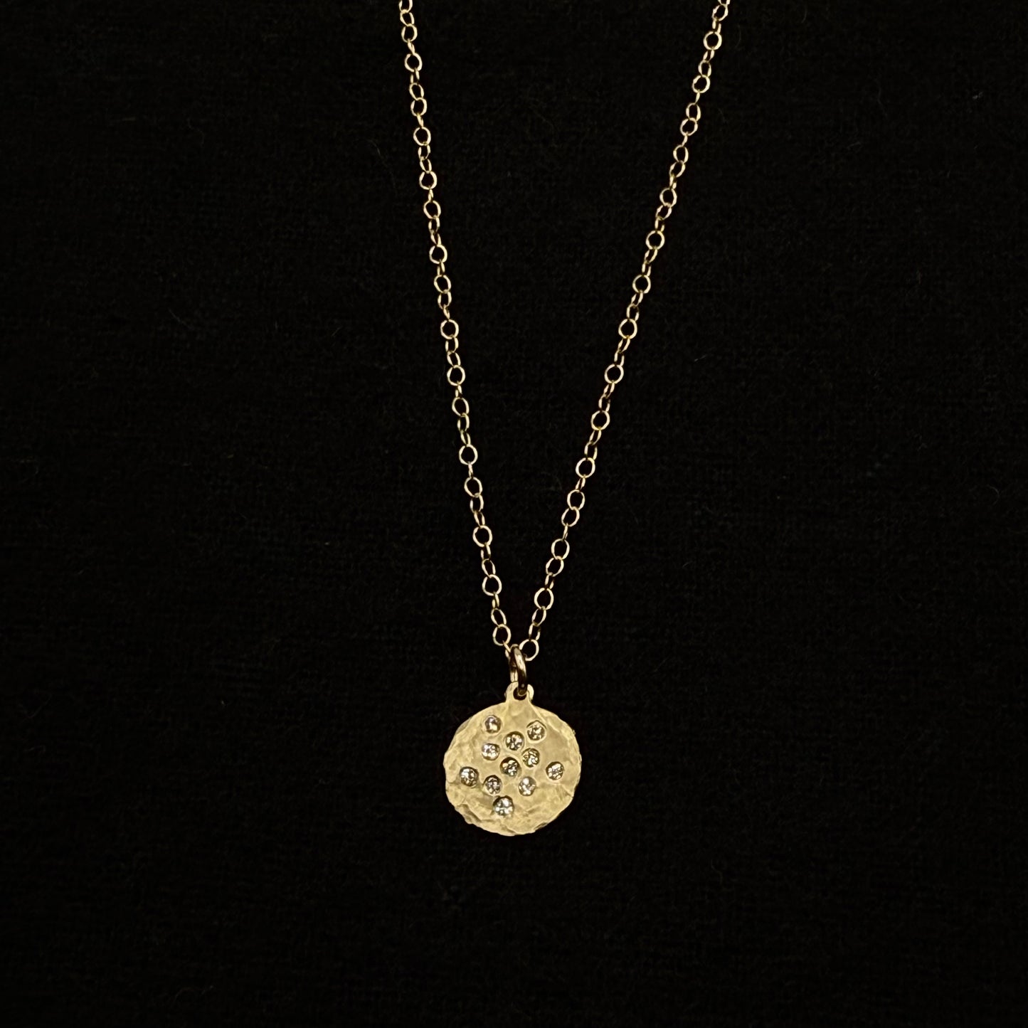 Gold round diamond splash disk pendant on a fine chain, close view