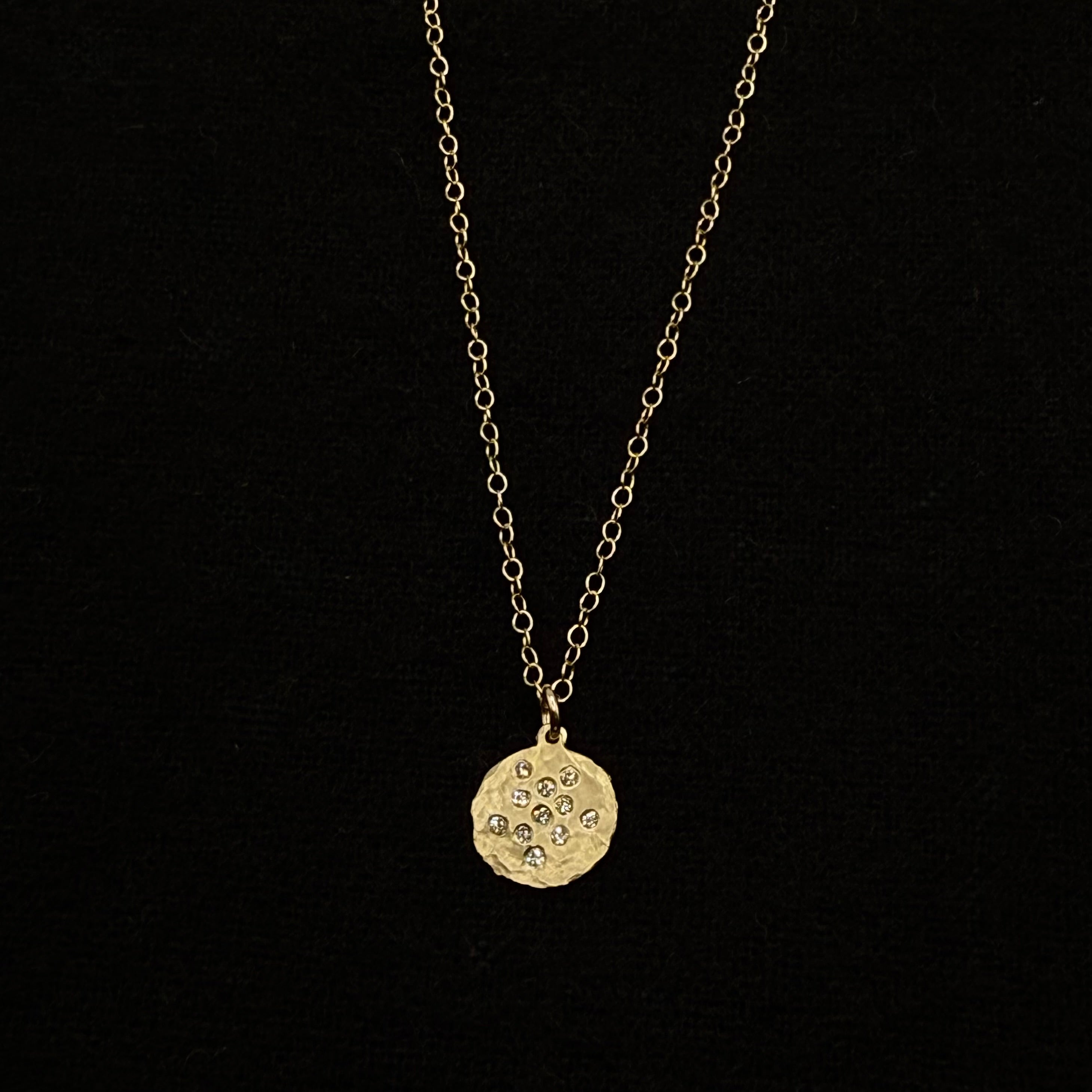 Gold round diamond splash disk pendant on a fine chain, close view