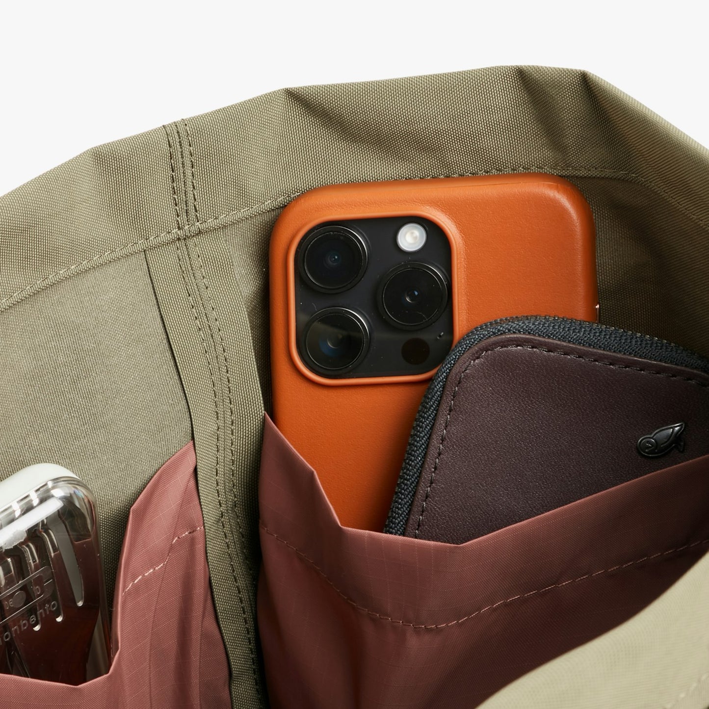 City tote bag close-up showing an orange phone in an inner pocket and brown card holder.