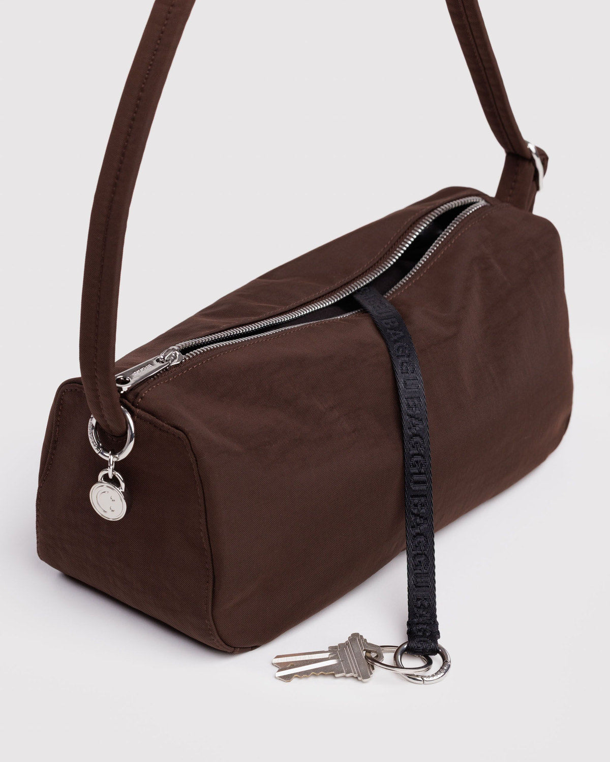 Brown nylon loaf bag close-up with zip front, key charm, and adjustable strap