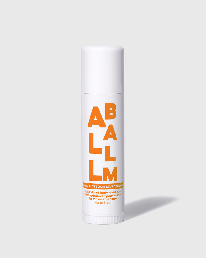 All balm stick with orange label on a white tube and a twist-up cap.