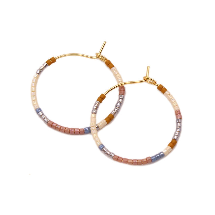 Two gold-tone beaded hoop earrings in neutral tones with hinged hooks