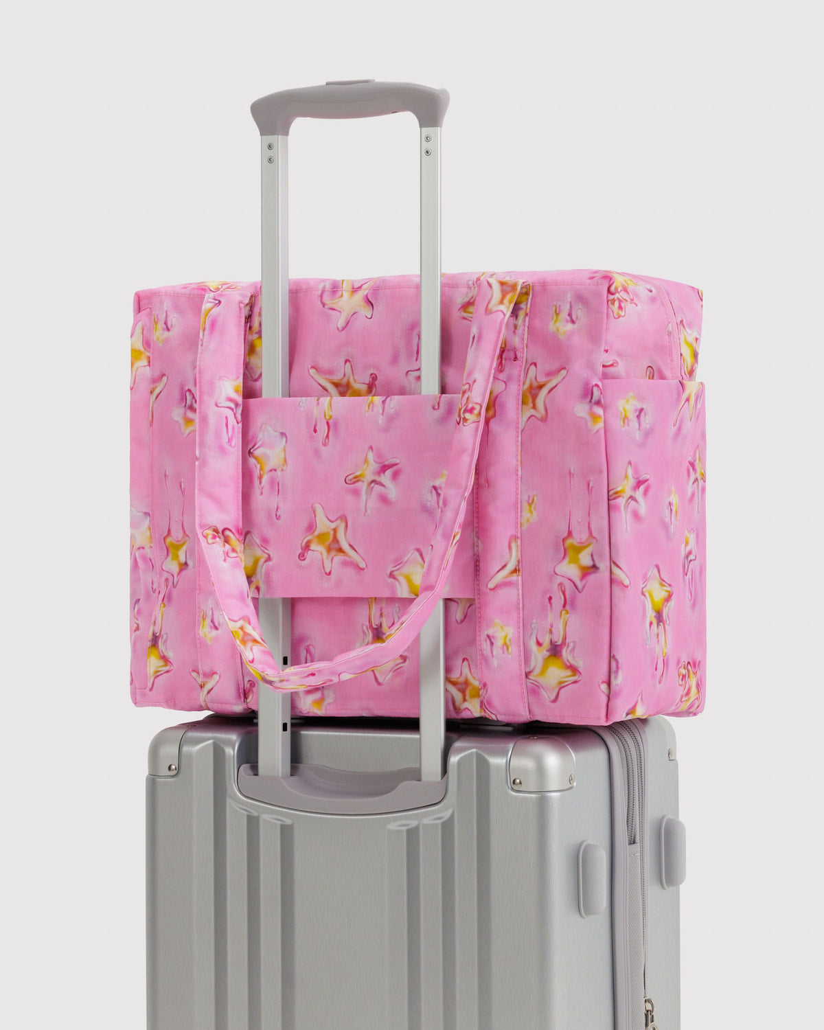 Small Cloud carry-on tote in pink star print on gray wheeled base with front strap
