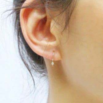 14-karat gold diamond drop earrings worn; round stone on a small hoop