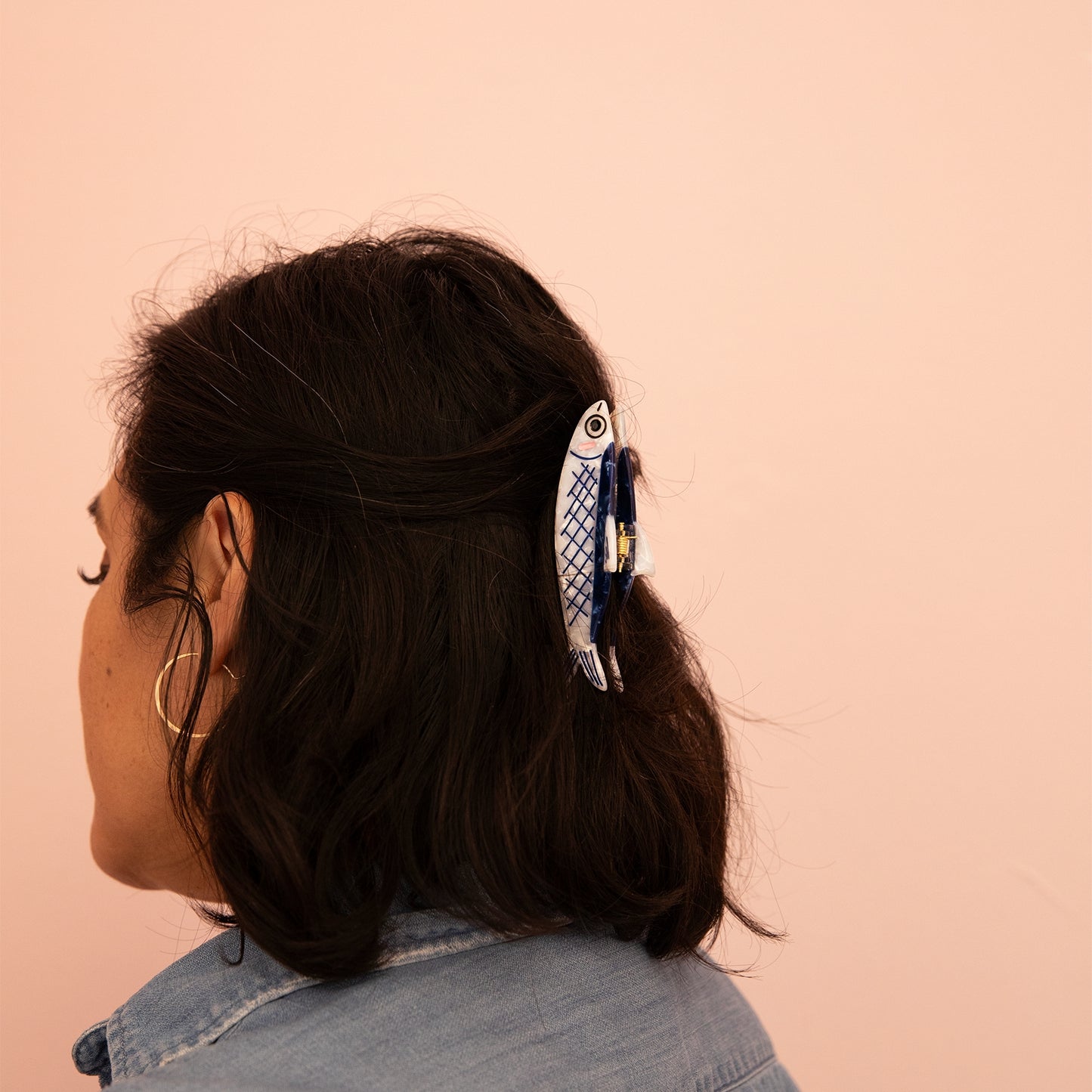 Fish-pattern hair claw clipped to dark hair, blue-and-cream fin design