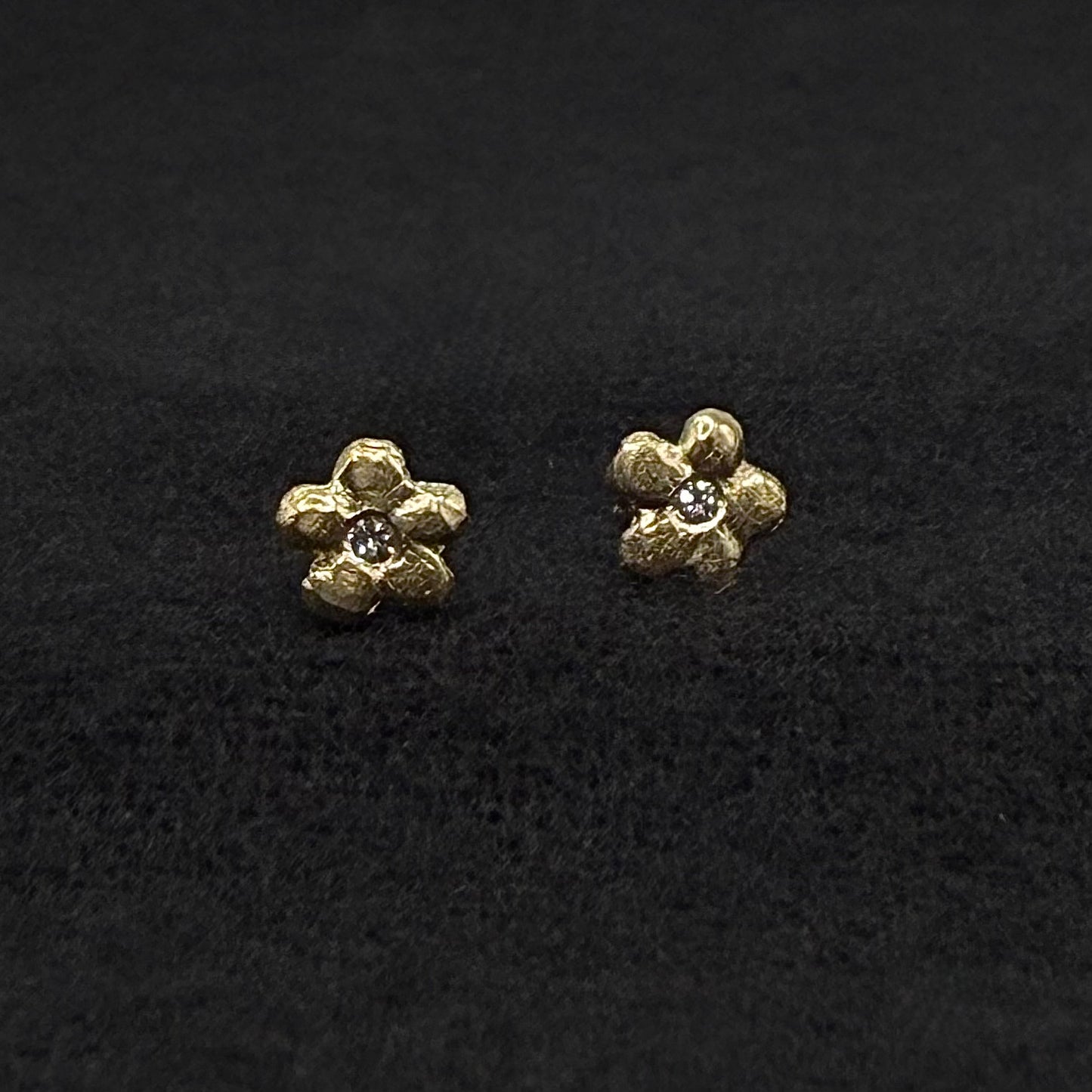 Close-up of 14k yellow gold flower stud earrings with diamond center details