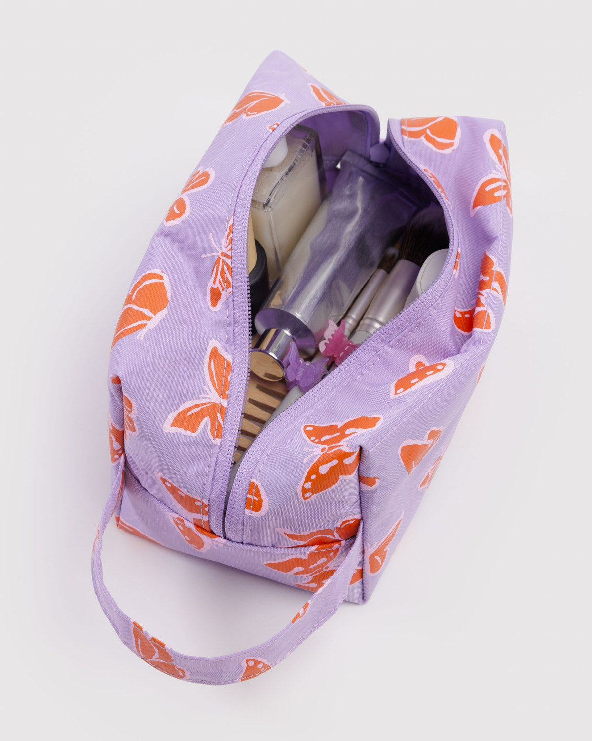 Dopp kit in lavender with orange butterfly print, open zip shows toiletries pockets