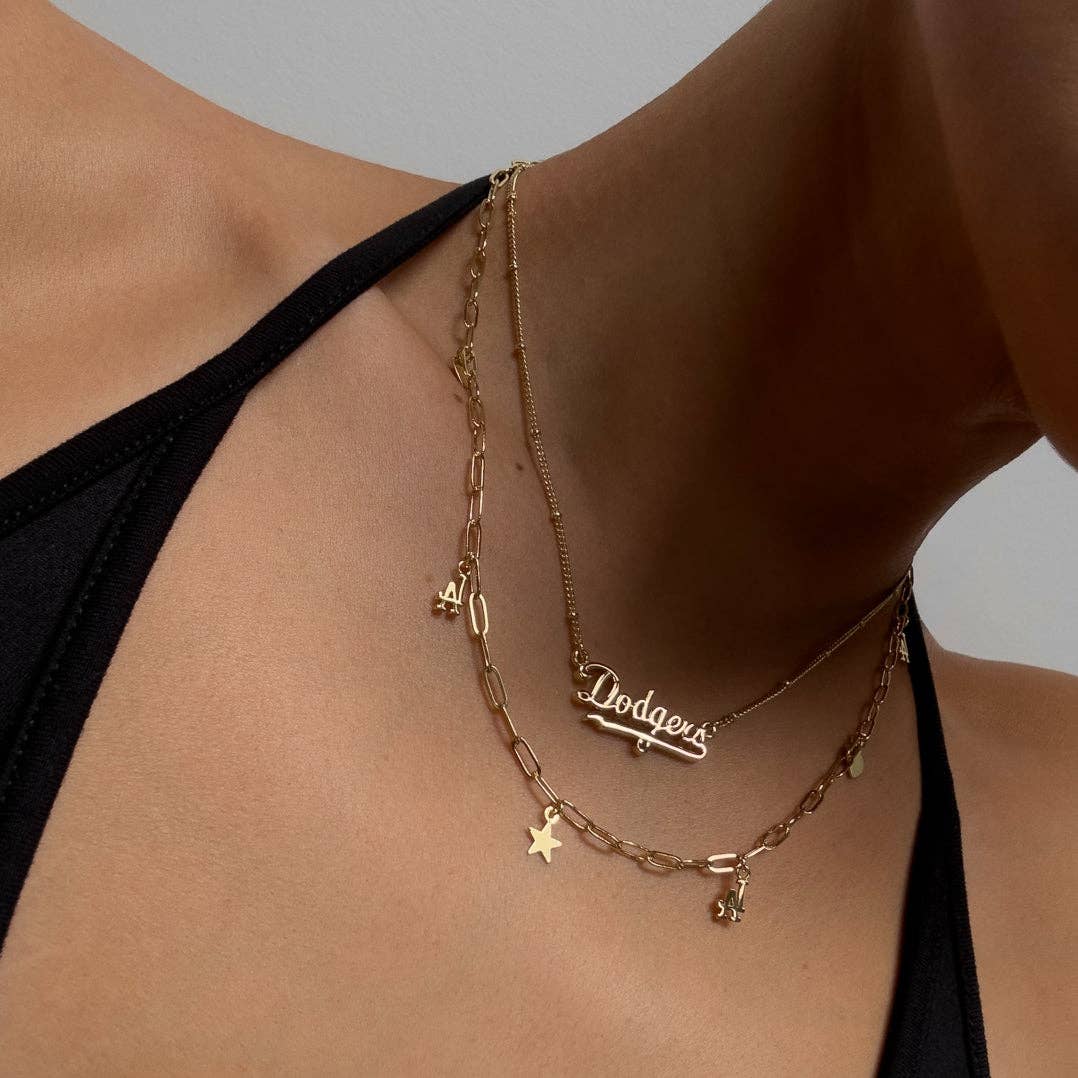 Gold charm necklace on neckline with Dodgers logo, heart and star pendants