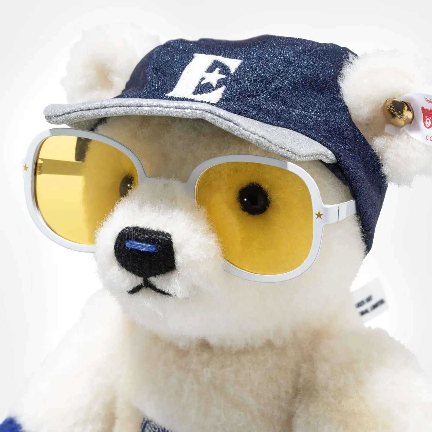 Cream teddy bear face with round yellow-lens sunglasses and navy blue cap