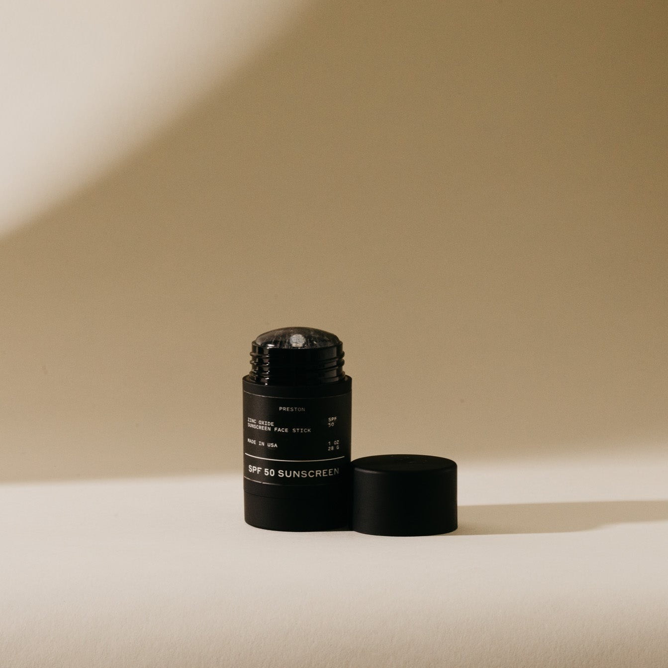 Black sunscreen stick with open cap and matching base