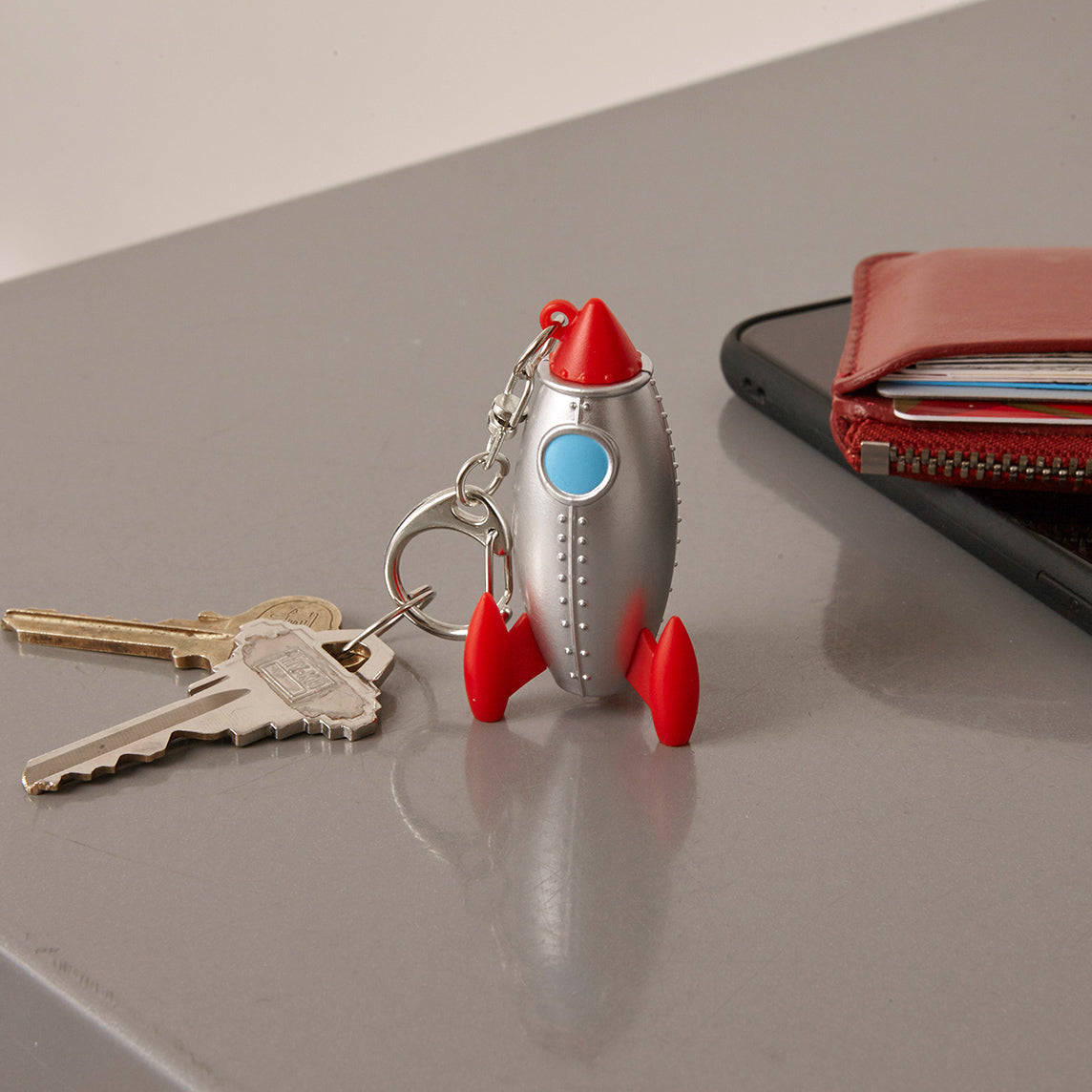 Rocket LED keychain with red nose, blue window, silver body, red fins, and keyring