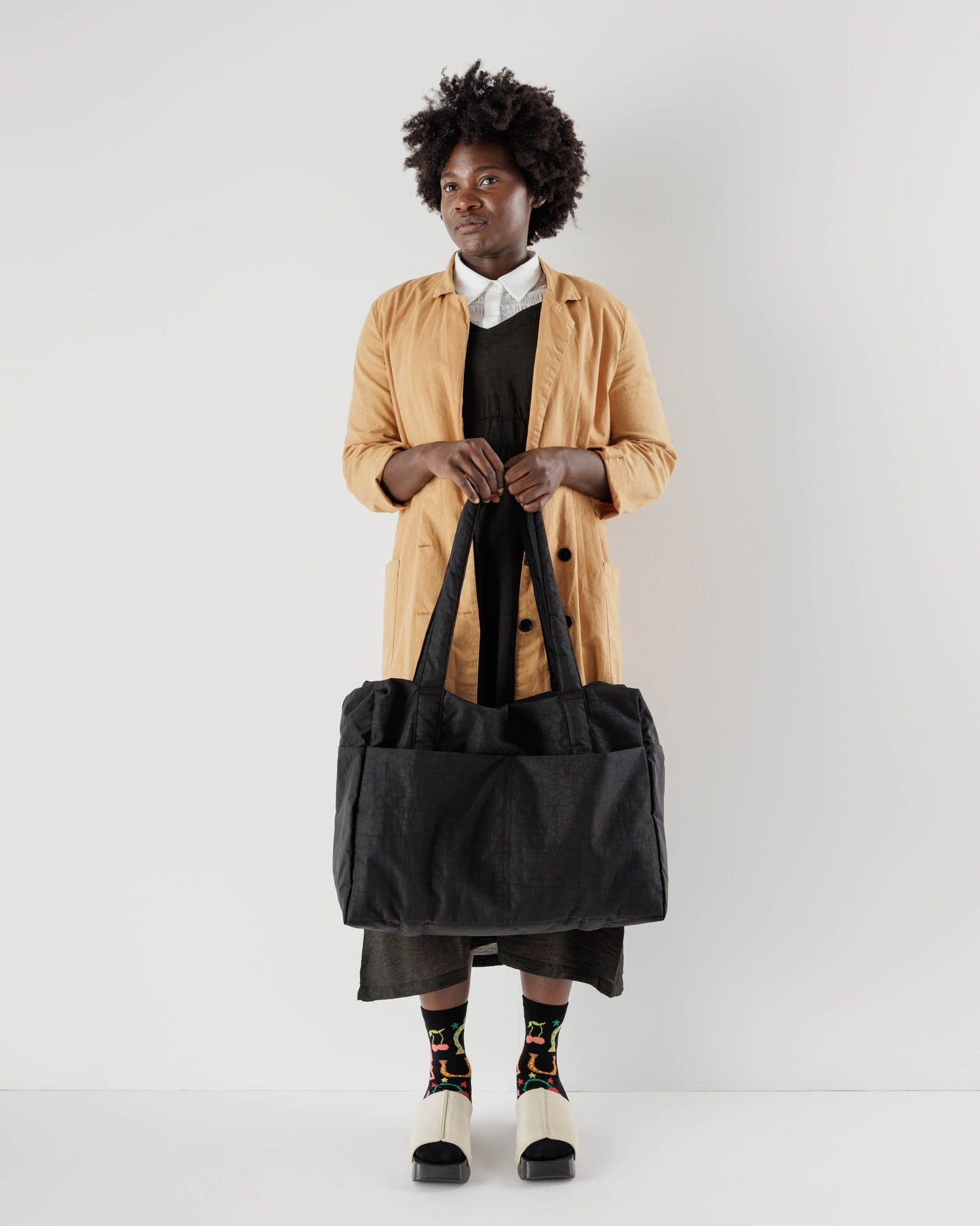 Carry-on travel bag in black with wide top handles and soft padded sides.